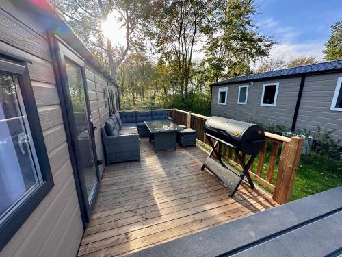 a deck with a couch and a grill on a house at Chalet Jersey in Lauwersoog