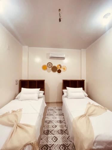 two beds in a room with white walls at Blue rose in Abu Simbel