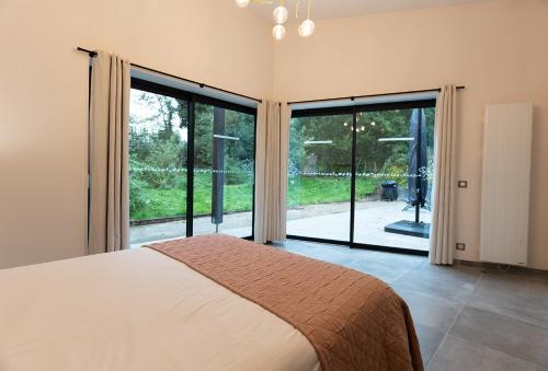 a bedroom with a bed and large sliding glass doors at Les Bobos à la ferme in La Madelaine-sous-Montreuil