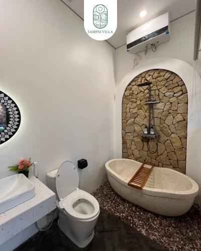 a bathroom with a stone tub and a toilet and sink at Sampai Villa Prambanan in Randugunting