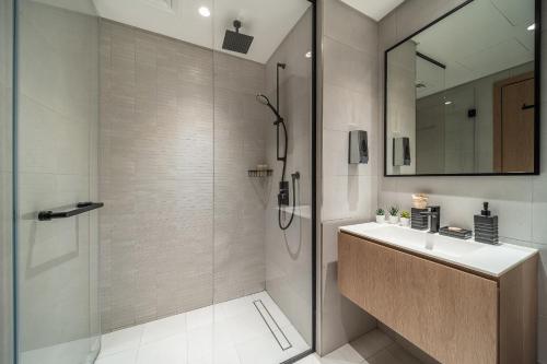 a bathroom with a shower and a sink and a mirror at Luxury Studios with Burj Khalifa View or Canal view - Marquise Square Tower in Dubai