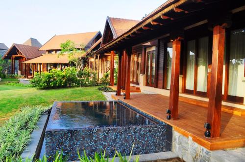 a house with a wooden deck and a pond at Anantaya Resort and Spa Passikudah in Pasikuda