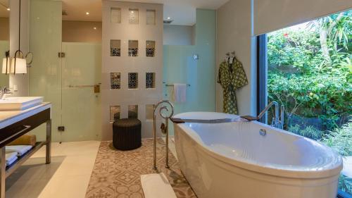 a large bathroom with a tub and a window at Samabe Bali Villas in Nusa Dua