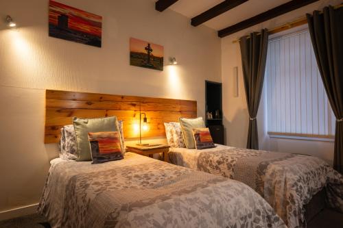 a hotel room with two beds and a window at The Trout Fly Guest House in Port Ellen
