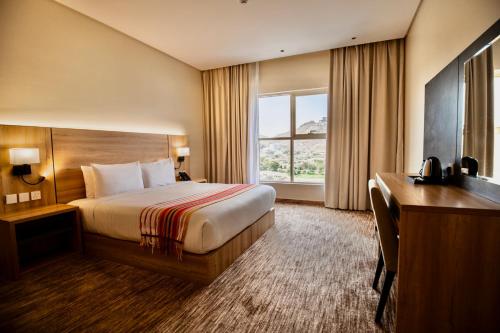 a hotel room with a bed and a desk and a window at W Suites Hotel Sama Abha in Abha