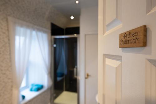 a bathroom with a door with a mirror and a window at The Trout Fly Guest House in Port Ellen