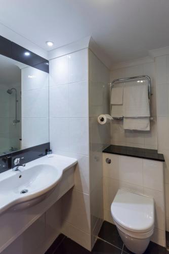a bathroom with a sink and a toilet and a mirror at Lakeside International Hotel in Camberley