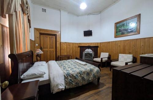 a bedroom with a bed and a desk and a fireplace at The Trevene Hotel in Nuwara Eliya
