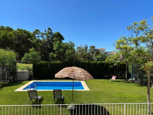 a pool with two chairs and an umbrella at Jacarandas Islantilla in Islantilla