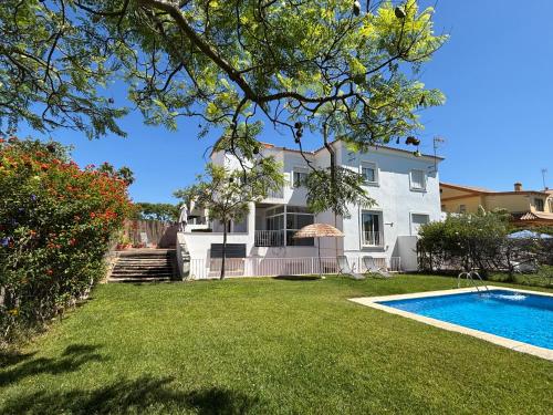 a house with a swimming pool in front of a yard at Jacarandas Islantilla in Islantilla