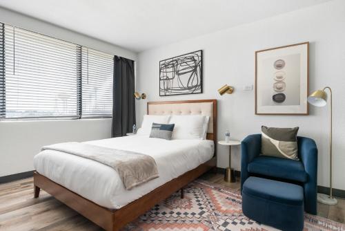 a bedroom with a bed and a blue chair at Lodgeur Upper Kirby, Houston - Close to Greenway Plaza, Galleria, Montrose in Houston