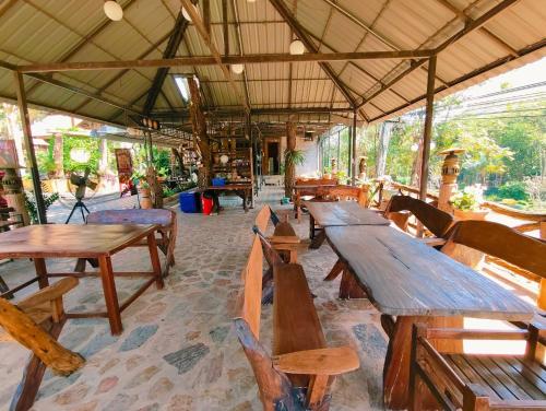 a group of wooden tables and chairs in a restaurant at Phakphing Erawan Homestay - พักพิง เอราวัณ โฮมสเตย์ in Tha Kradan