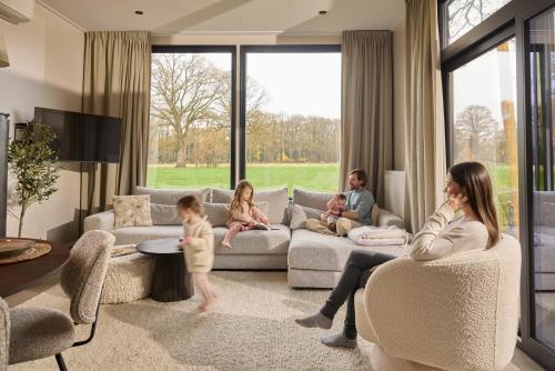 a family is sitting in a living room at Slow Living bij Mölke x Wellnesslodges in Zuna