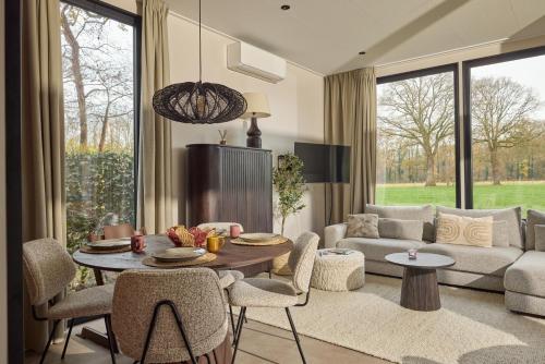 a living room with a couch and a table and chairs at Slow Living bij Mölke x Wellnesslodges in Zuna