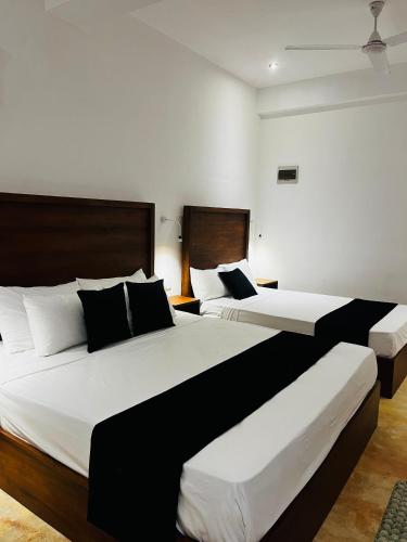 two beds in a room with white and black at BlueTide Hiriketiya in Hiriketiya