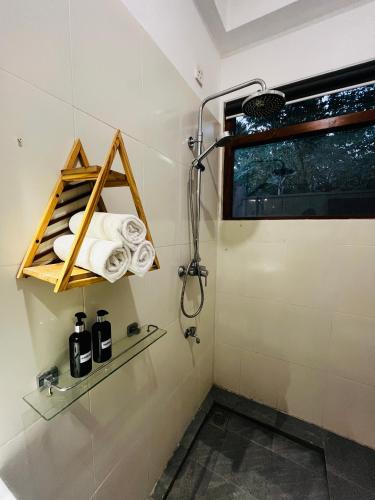 a bathroom with a shower and towels on a wall at BlueTide Hiriketiya in Hiriketiya