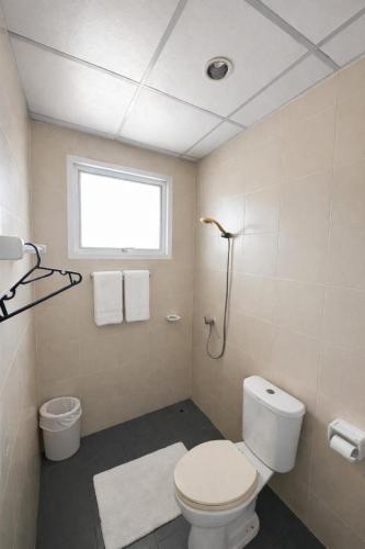 a bathroom with a white toilet and a window at Leo Guest House in Khao Lak