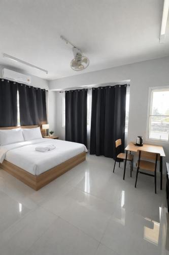 a bedroom with a bed and a desk and a table at Leo Guest House in Khao Lak