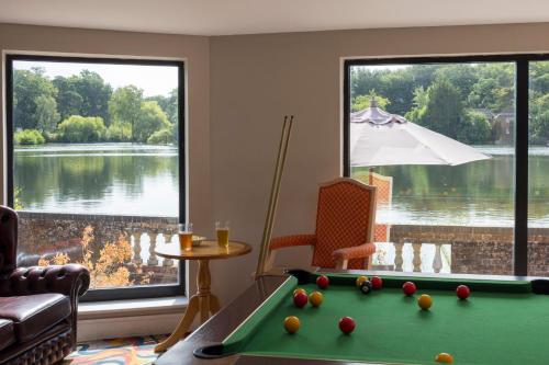 a living room with a pool table and a large window at Lakeside International Hotel in Camberley