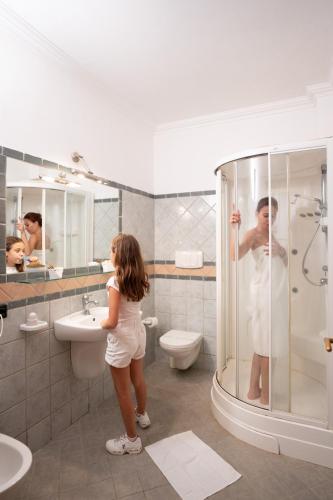 a woman standing in a bathroom with a shower at Triscinamare Hotel Residence in Triscina