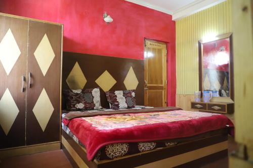 a bedroom with a bed with a red wall at backpacker's stop in Jagatsukh