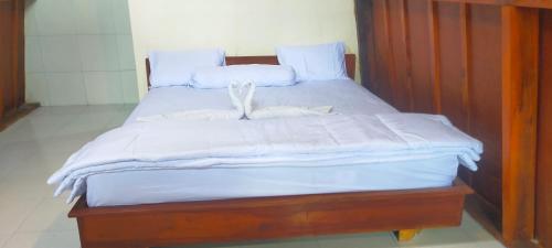 a wooden bed with white sheets and white pillows at SKY SUNSET Bungalows in Tetebatu