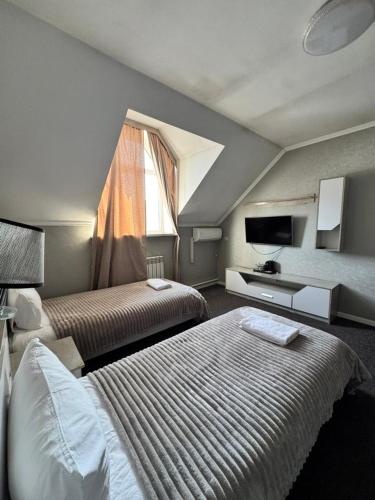 una camera d'albergo con due letti e una televisione di Garnet hotel a Bishkek