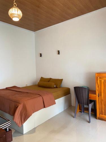 a bedroom with a bed and a desk and a chair at Raya Homestay in Kuta Lombok