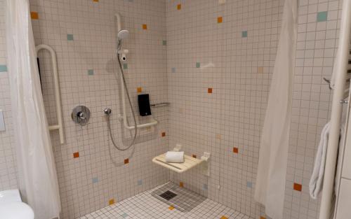 a white tiled bathroom with a shower and a sink at centrovital Hotel Berlin in Berlin