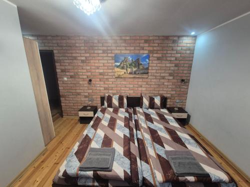 a bed in a room with a brick wall at Къща за гости Белоградчик in Belogradchik