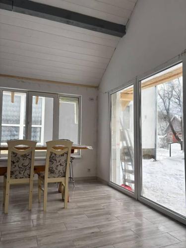 a dining room with a table and chairs and windows at Mini Хаус Ясіня in Yasinya