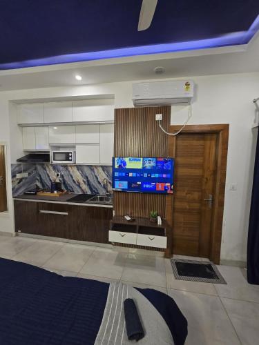 a room with a kitchen with a tv and a door at The Mulberry Silk - Blue Saphire in Noida