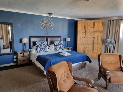 a blue bedroom with a bed and a chair at 19th Hole Golf Villa Guesthouse in Worcester