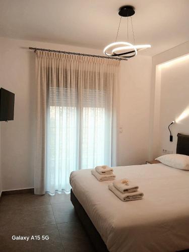 a bedroom with a bed and a window with towels on it at Lygonis White Houses in Mitika