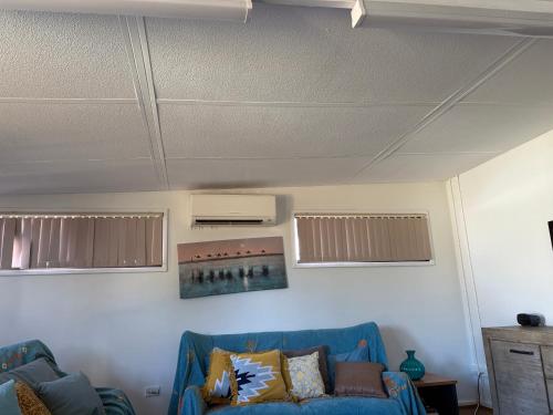 a living room with a blue couch and windows at Budget rooms in big house in Kelmscott