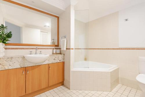 a bathroom with a sink and a toilet and a tub at The Breakers Yamba in Yamba