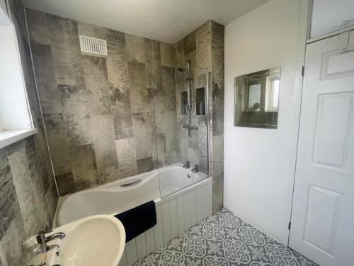 a bathroom with a tub and a sink and a shower at Spacious 5-Bedroom Home with Garden & Parking Near Station in Coventry