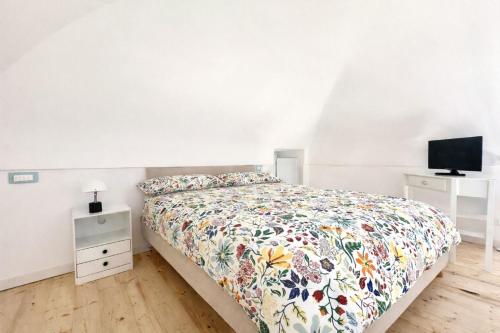 a bedroom with a bed with a floral bedspread and a television at Dimora Rosella in Tramonti