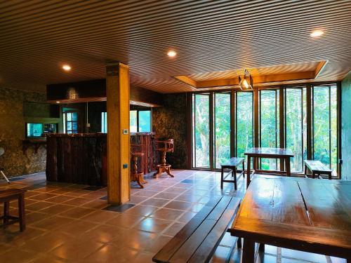 a living room with a table and some windows at Phakphing Erawan Homestay - พักพิง เอราวัณ โฮมสเตย์ in Tha Kradan