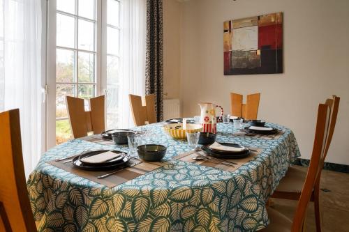 a dining room table with a blue and green table cloth at Maison Le Reflet de Marne - Welkeys in Vaires-sur-Marne
