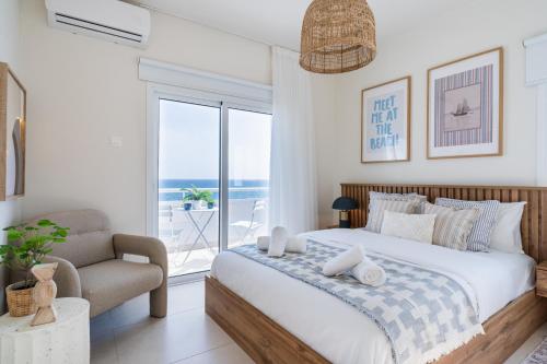 a bedroom with a bed and a chair and a window at Compass 1-BR Apartment by Makenzy Beach in Larnaca