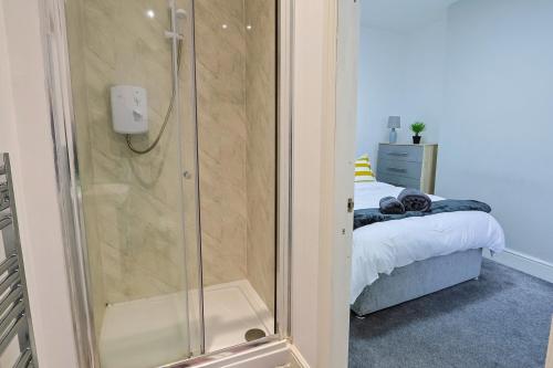 a shower with a glass door next to a bed at Elevate suites Darlington in Darlington