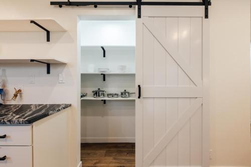 a barn door in a kitchen with white cabinets at Extended Stay SoCo Oasis Outdoor TV, Heavenly Bed, Long Stay Ready in Austin