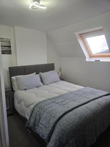 a bed in a white room with a window at Tor's Place in Portree