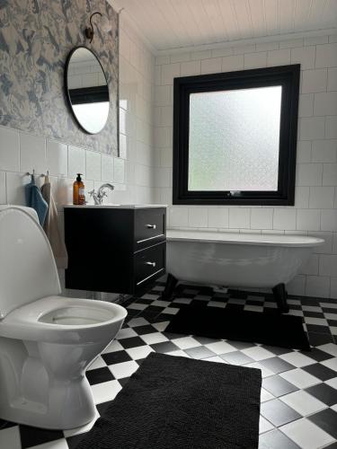 a bathroom with a tub and a toilet and a window at Chilla villa in Leryd
