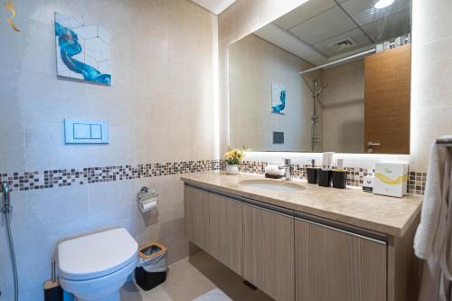 a bathroom with a sink and a toilet and a mirror at Yas Island 1BR - Chic Luxe Retreat in Abu Dhabi