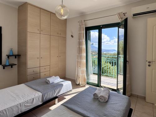 a bedroom with two beds and a large glass window at Villa Yianna in Karavádhos