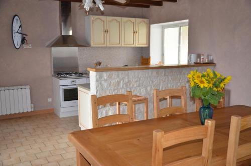 a kitchen with a wooden table with a vase of flowers at Les lilas in Lhommaizé