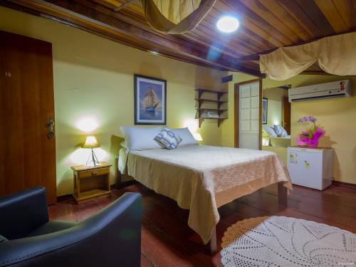 a bedroom with a bed and a chair in it at Pousada Talismã in Paraty