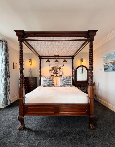 a bedroom with a wooden canopy bed with white sheets at Chandlers BnB in Seahouses